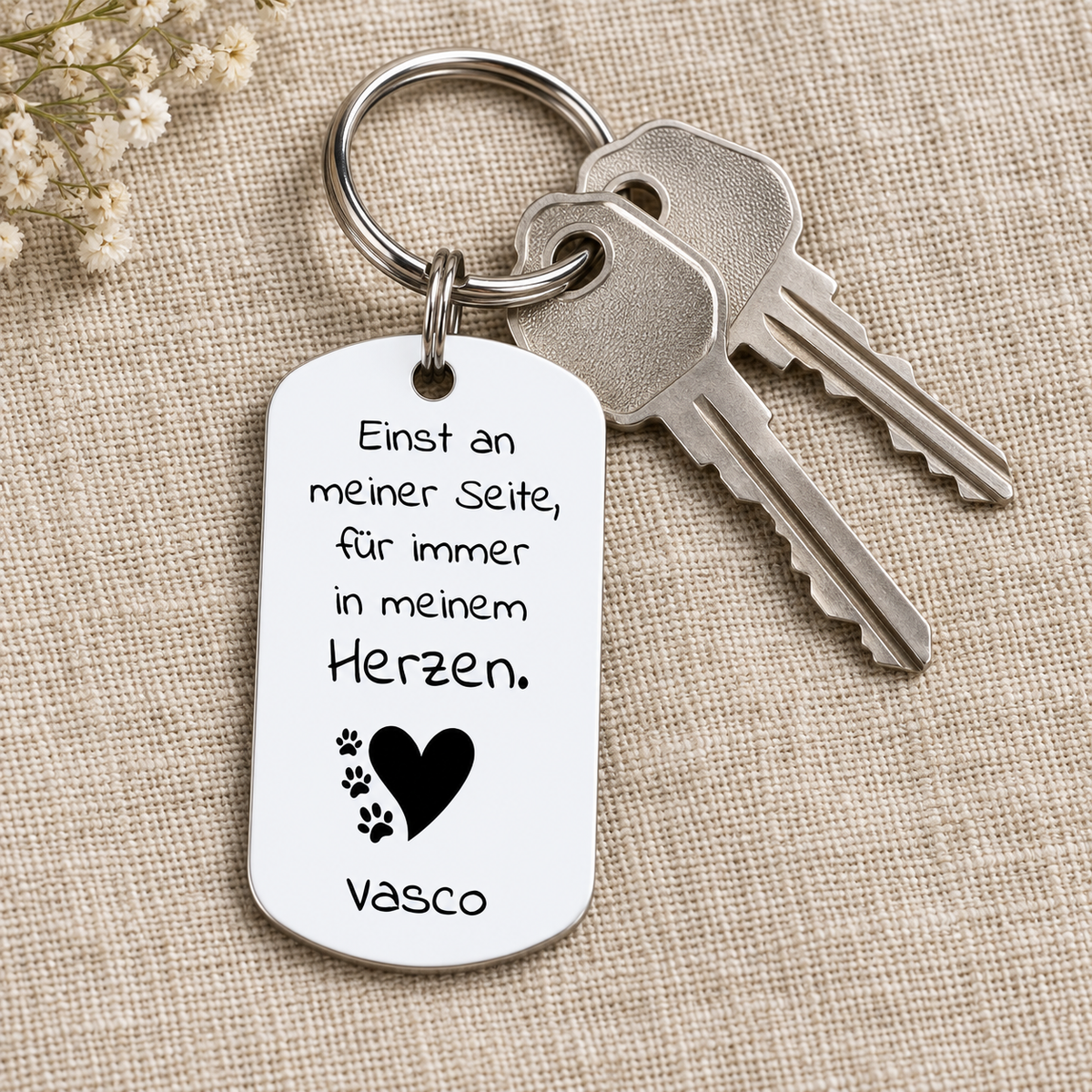 Personalisierter Schlüsselanhänger aus Metall mit weißer Oberfläche und schwarzer Schrift.