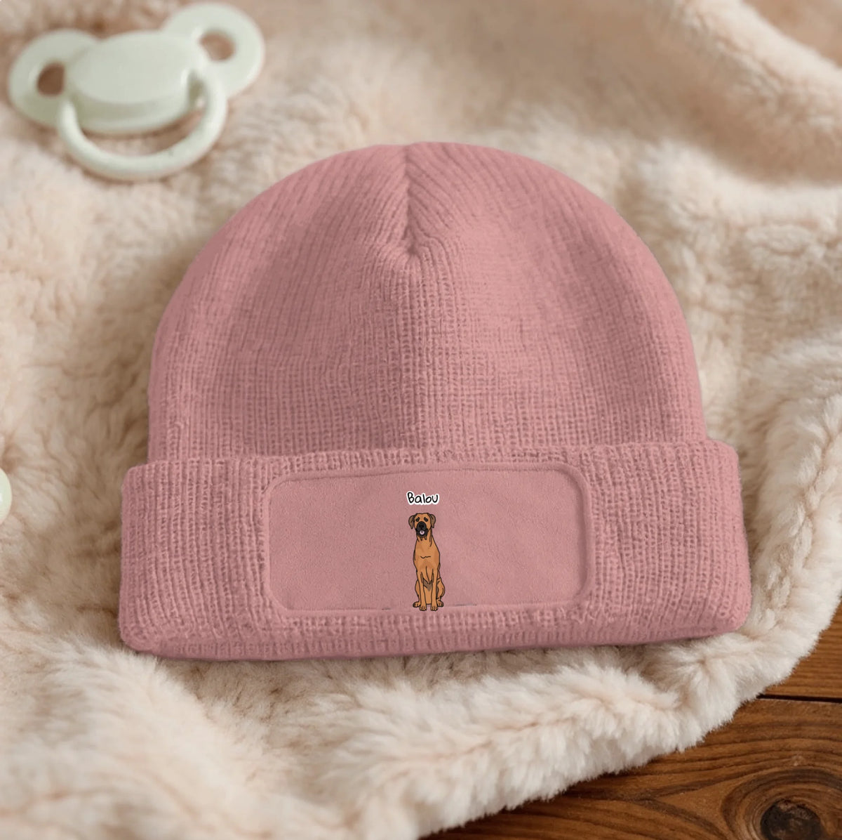 Rosa Beanie aus gestricktem Material mit Hundemotiv und Textfeld.