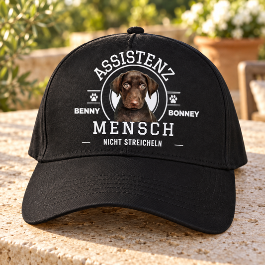 Schwarze Cap mit Aufdruck "ASSISTENZ MENSCH", Hundebild und dem Text "NICHT STREICHEN".