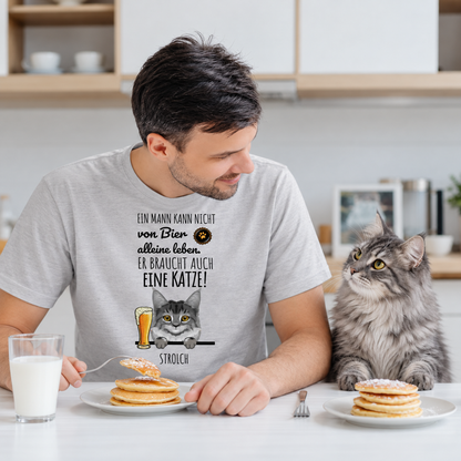 Personalisierte graue T-Shirt mit lustigem Katzendesign und Spruch über Bier, getragen von einem Mann am Tisch.
