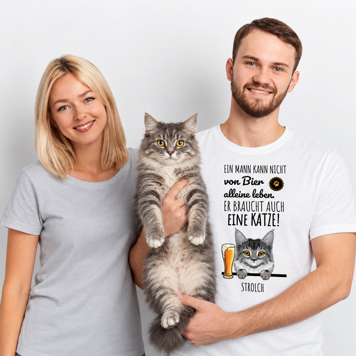 Personalisiertes T-Shirt mit Katzenmotiv und Spruch. Farbe: Weiß. Träger hält Katze, daneben steht eine Frau.