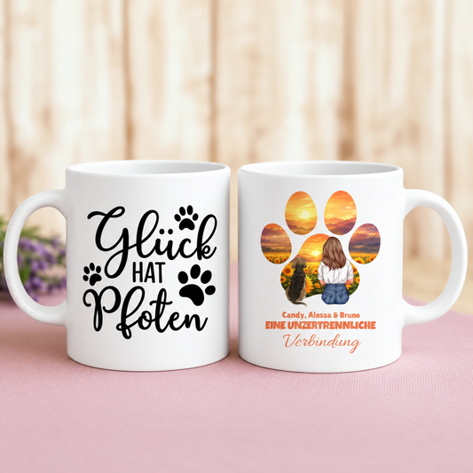 Personalisierte Kaffeetasse mit aufgedrucktem Text und Pfotenmotiven in Weiß und buntem Design.