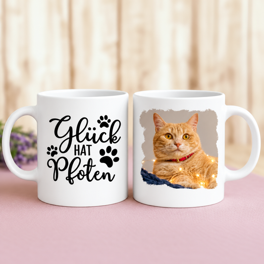 Personalisierte Tasse mit dem Schriftzug „Glück hat Pfoten“ und einem Foto einer orangefarbenen Katze.