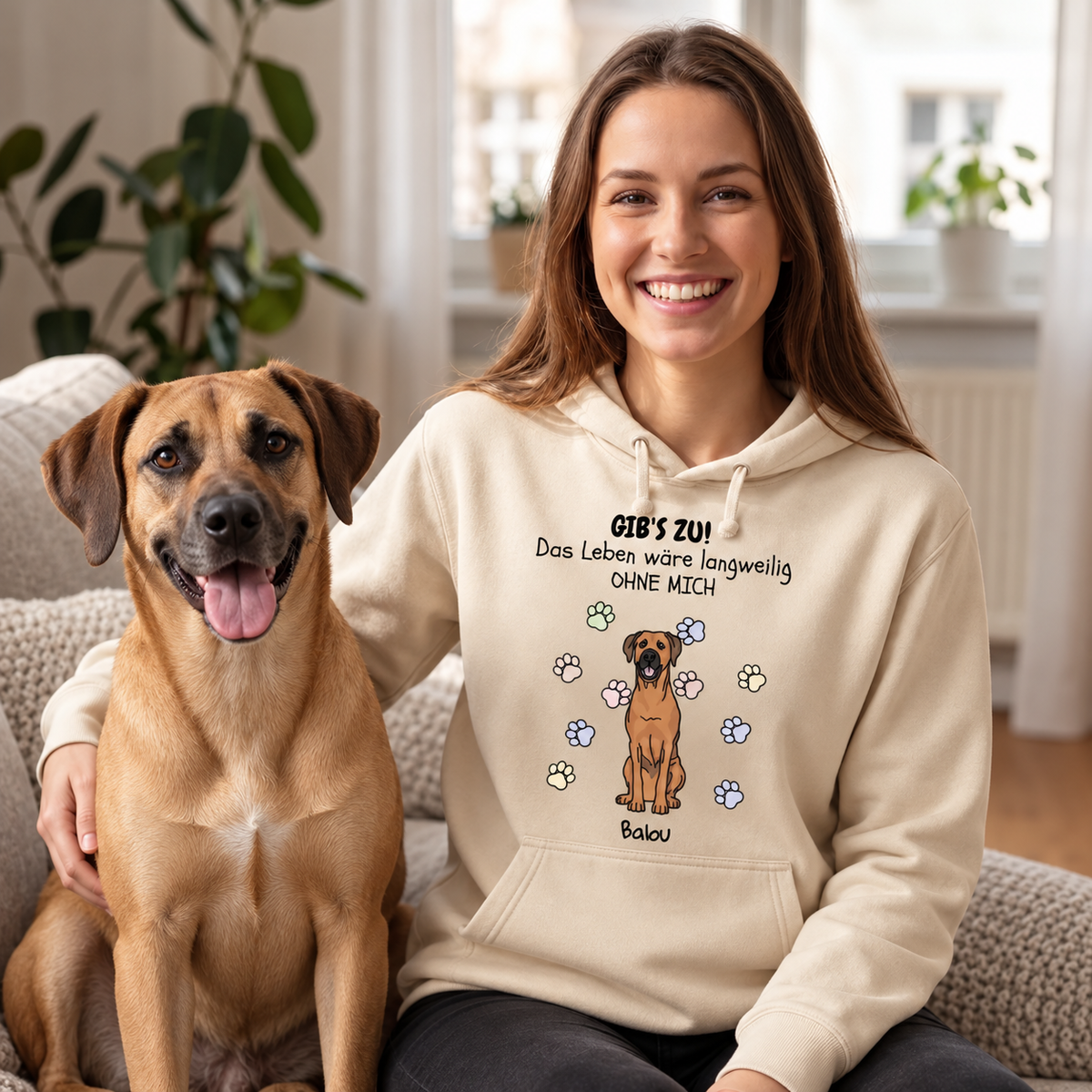 Beige Hoodie mit Hundemotiv und Text "Das Leben wäre langweilig OHNE MICH", Trägerin mit Hund auf dem Sofa.