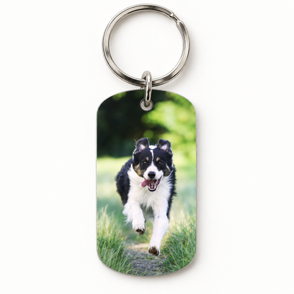 Schlüsselanhänger aus Metall mit Foto eines laufenden Hundes auf grünem Hintergrund.
