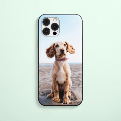 Handyhülle mit Foto eines sitzenden Hundes am Strand, schwarze Umrandung.
