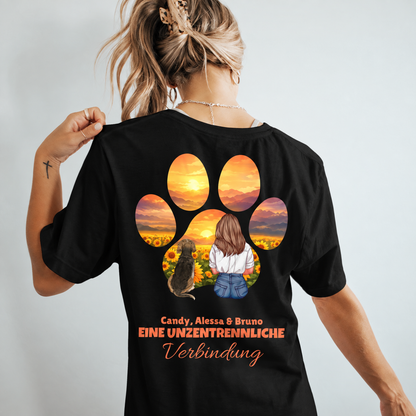 Schwarzes T-Shirt mit buntem Motiv einer Frau und Hund vor Sonnenaufgang in Pfotenform. Personalisiert mit Namen.
