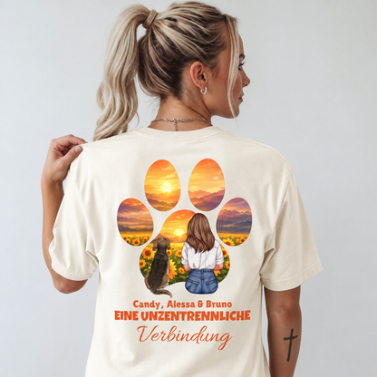Beige T-Shirt mit farbigem Druck einer Frau und einem Hund vor einer Sonnenblumenlandschaft.