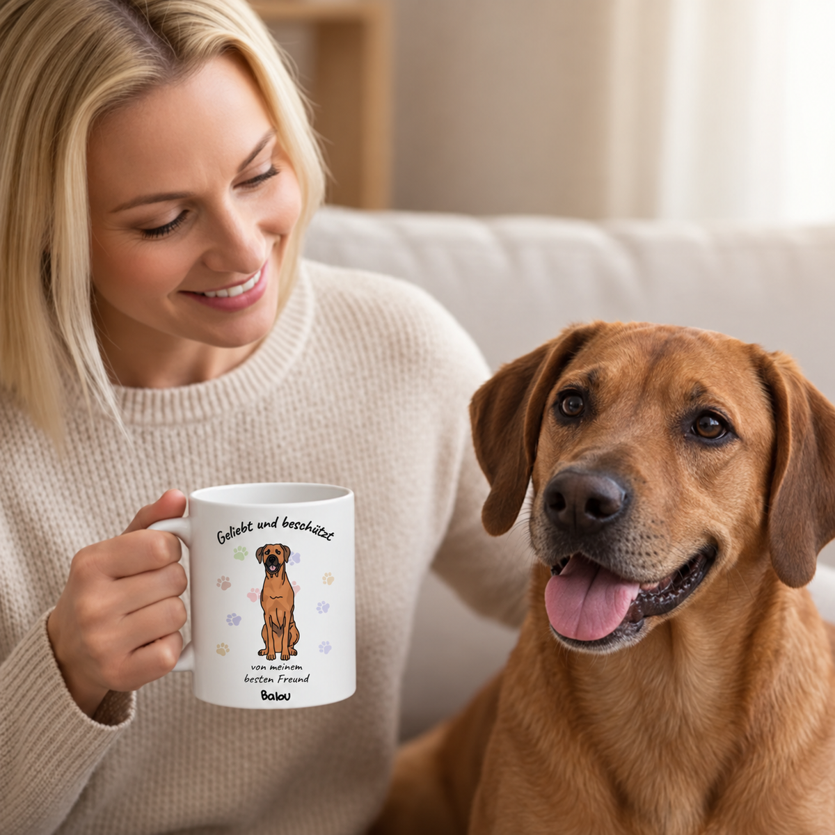 Person hält eine personalisierte Tasse mit Hundemotiv, weiß mit Aufschrift und bunten Pfotenabdrücken.