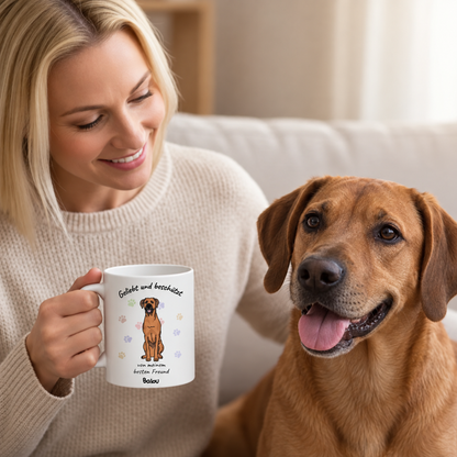 Person hält eine personalisierte Tasse mit Hundemotiv, weiß mit Aufschrift und bunten Pfotenabdrücken.