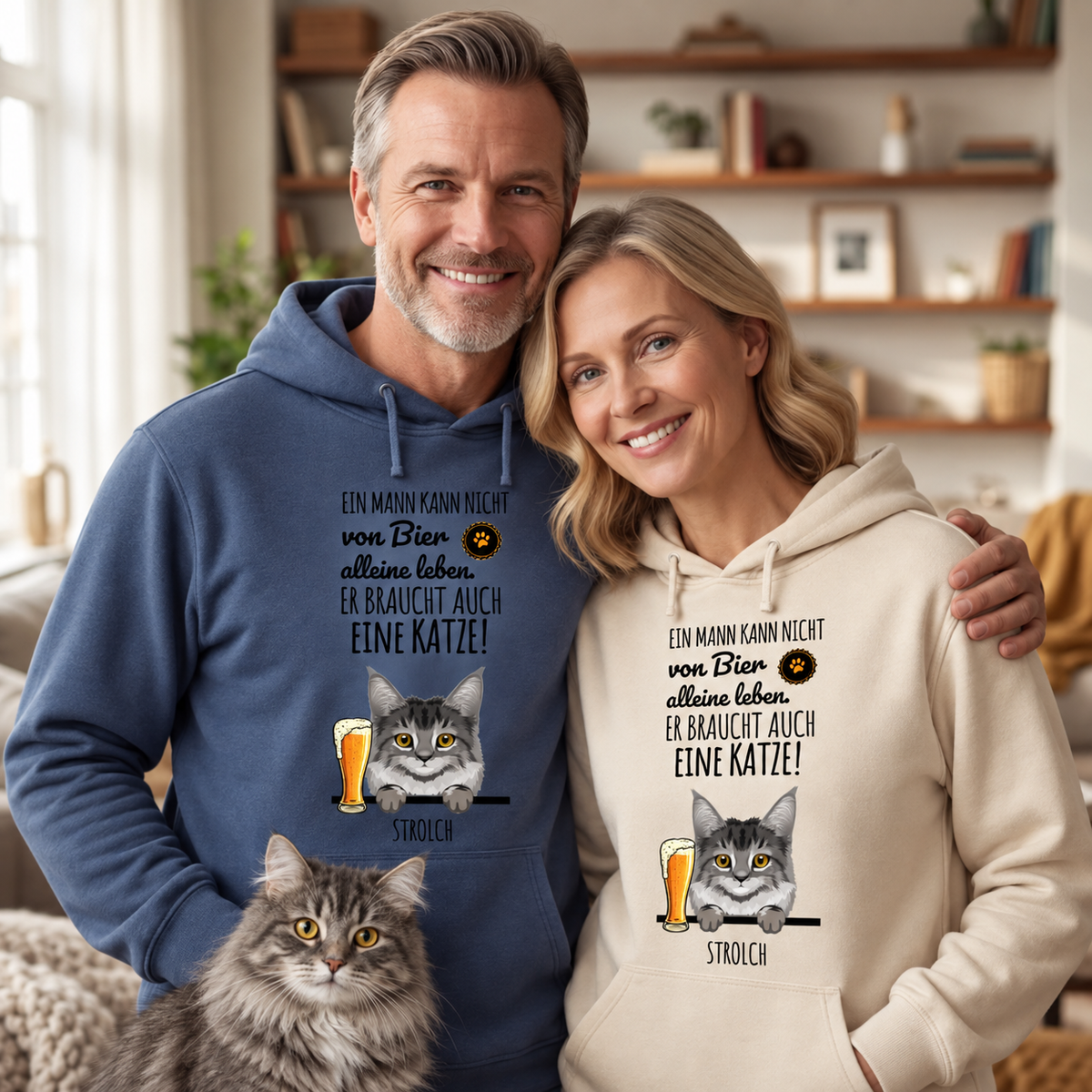 Zwei Personen in Hoodies, einer dunkelblau und einer beige, mit Katzenmotiven und Sprüchen. Katze sitzt davor.