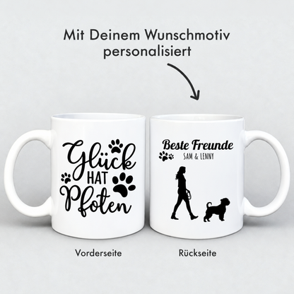 Personalisierte weiße Tasse mit schwarzem Aufdruck „Glück hat Pfoten“ und Silhouette einer Person mit Hund.