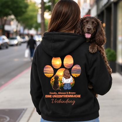 Schwarzer Hoodie mit farbigem Motiv einer Person und Hund sowie Schriftzug "Eine unzertrennliche Verbindung" auf dem Rücken.