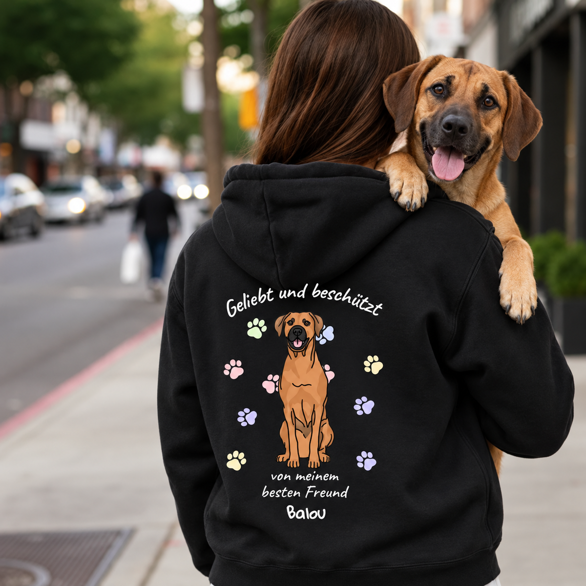 Schwarzer Hoodie mit buntem Hundemotiv und Schriftzug "Geliebt und beschützt" auf dem Rücken.