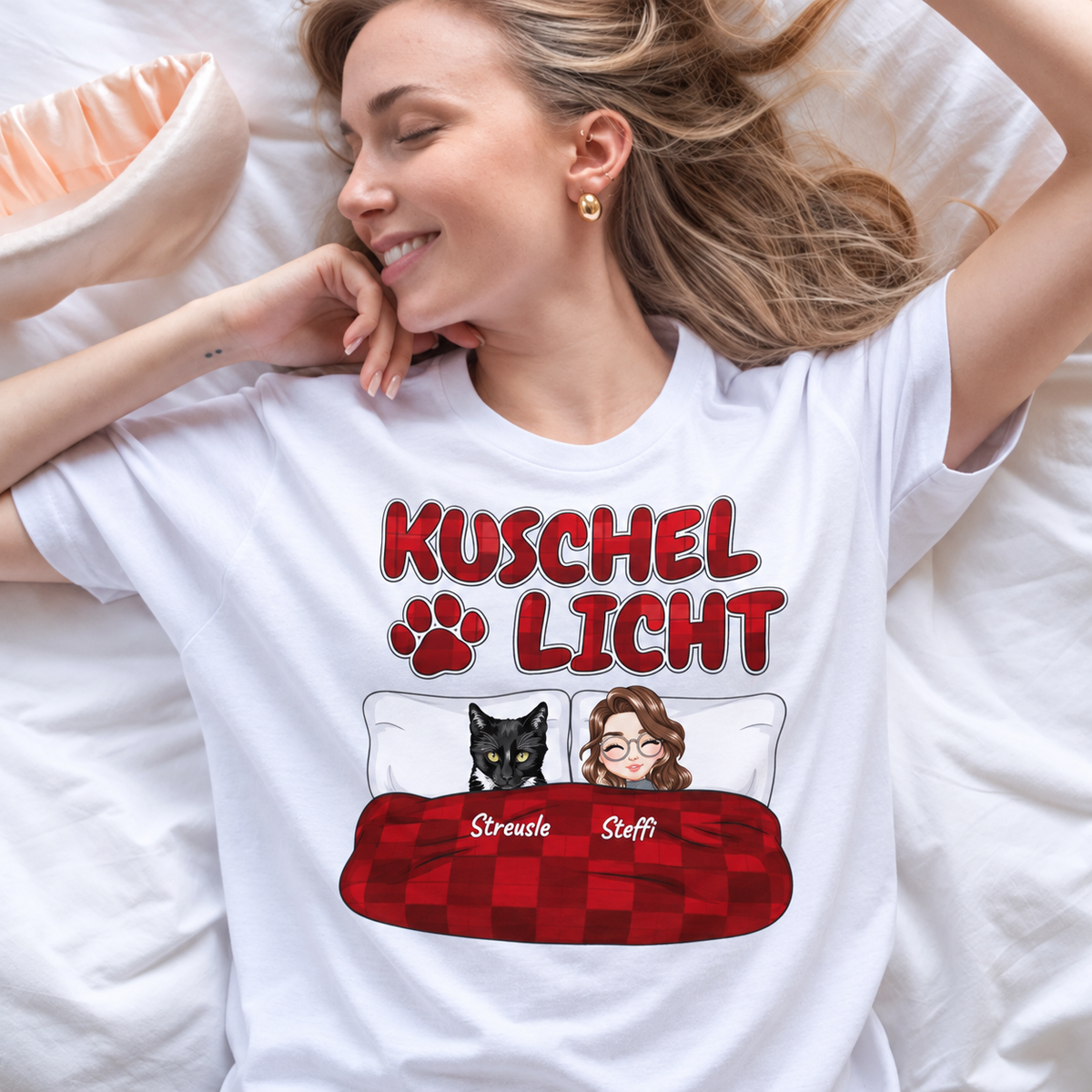 Weißes T-Shirt mit dem Aufdruck "Kuschel Licht", zeigt eine Zeichnung einer Frau und einer Katze im Bett.
