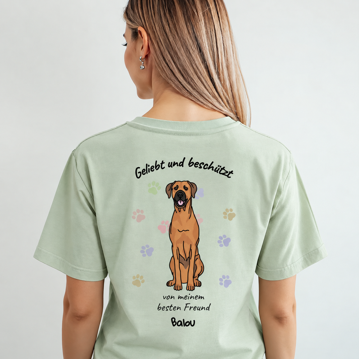 Hellgrünes T-Shirt mit Hundedruck und Text "Geliebt und beschützt" auf Rückseite.