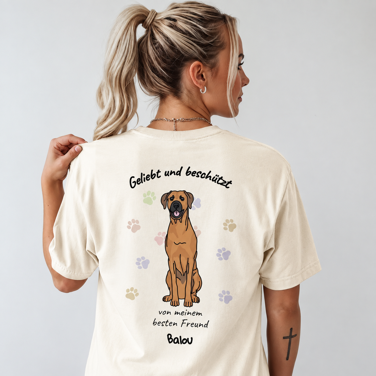 Beige T-Shirt mit Hundedesign und dem Text "Geliebt und beschützt" auf der Rückseite.