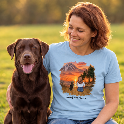 Blaues T-Shirt mit grafischem Druck einer Frau und ihrem Hund vor einer Berglandschaft.