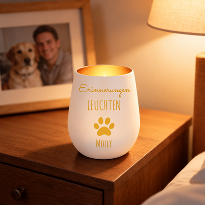 Personalisiertes Trauerlicht in weiß mit goldener Schrift und Pfotenmotiv, steht auf einem Holztisch.