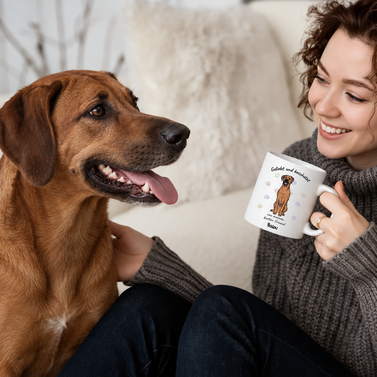 Person mit braunem Hund hält eine personalisierte Tasse mit dem Aufdruck "Geliebt und beschützt".