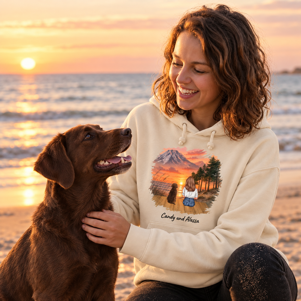 Beige Hoodie mit Tiermotiv, Trägerin mit Hund am Strand bei Sonnenuntergang.