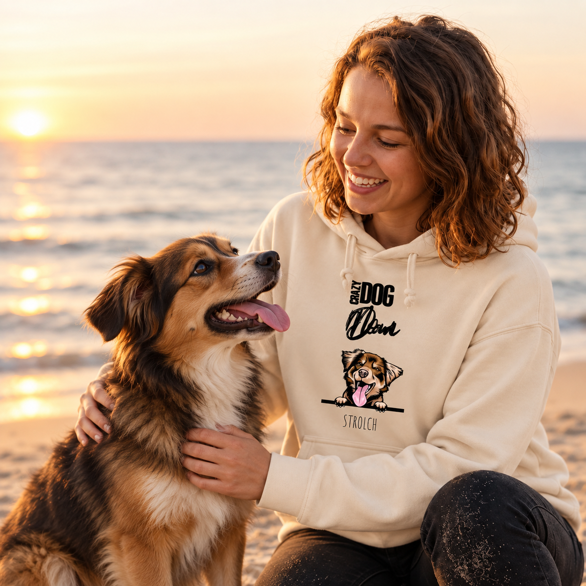 Beige Hoodie mit Hundemotiv, getragen von einer Person am Strand bei Sonnenuntergang.