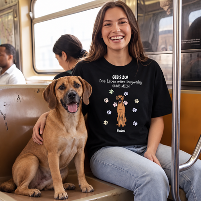 Schwarzes T-Shirt mit Aufdruck, Text und Hundebild, getragen von lächelnder Frau in einem Zug. Hund sitzt neben ihr.