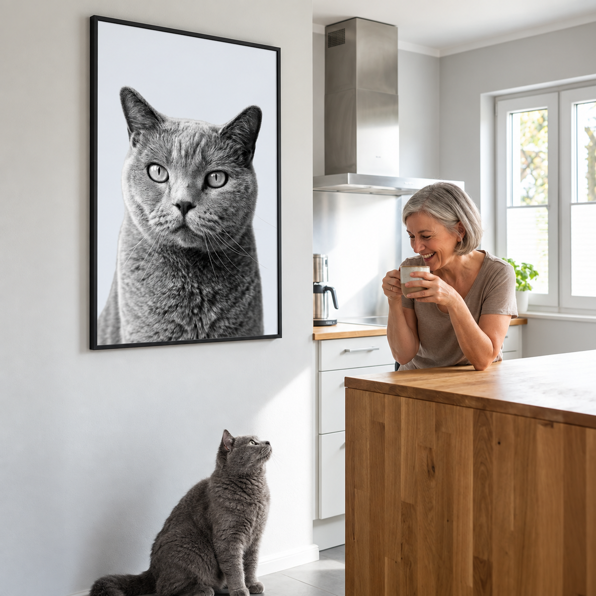 Person zeigt lächelnd ein personalisiertes Haustierportrait eines grauen Katers an der Wand.