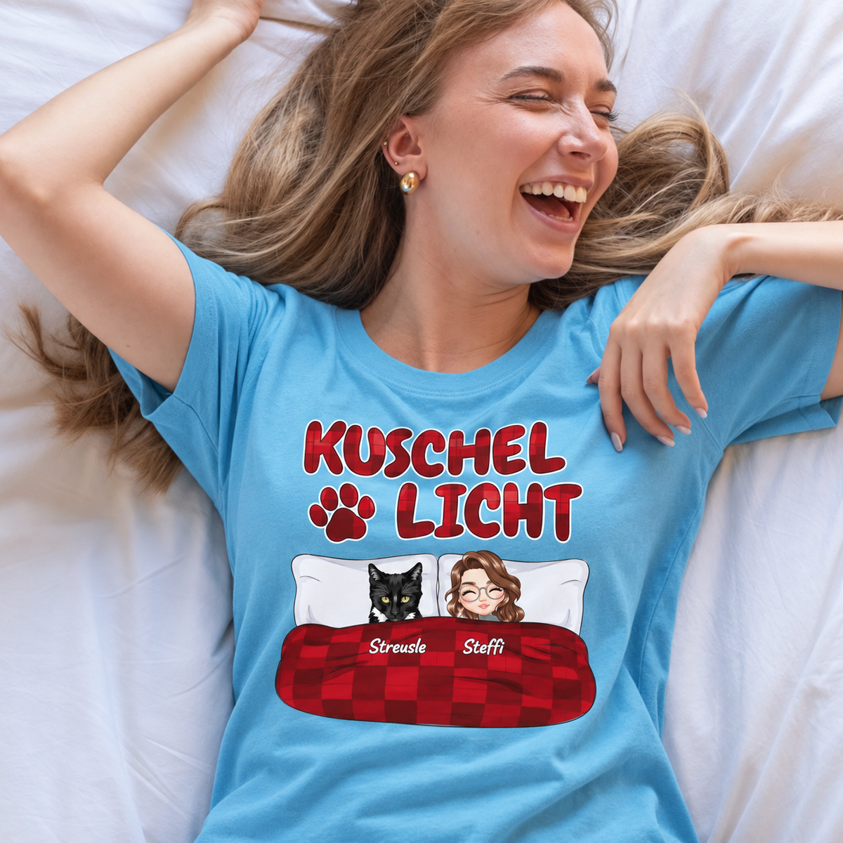 Blaues T-Shirt mit dem Aufdruck "Kuschel Licht" und grafischen Elementen von zwei Personen und einem schwarzen Tier.