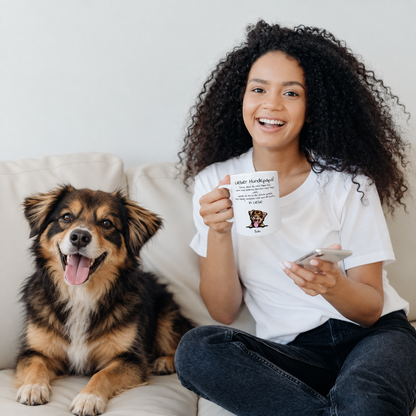 Frau mit personalisierter Tasse „Lieber Hundepapa“ sitzt neben Hund auf einer Couch. Tasse zeigt Hundebild und Text.
