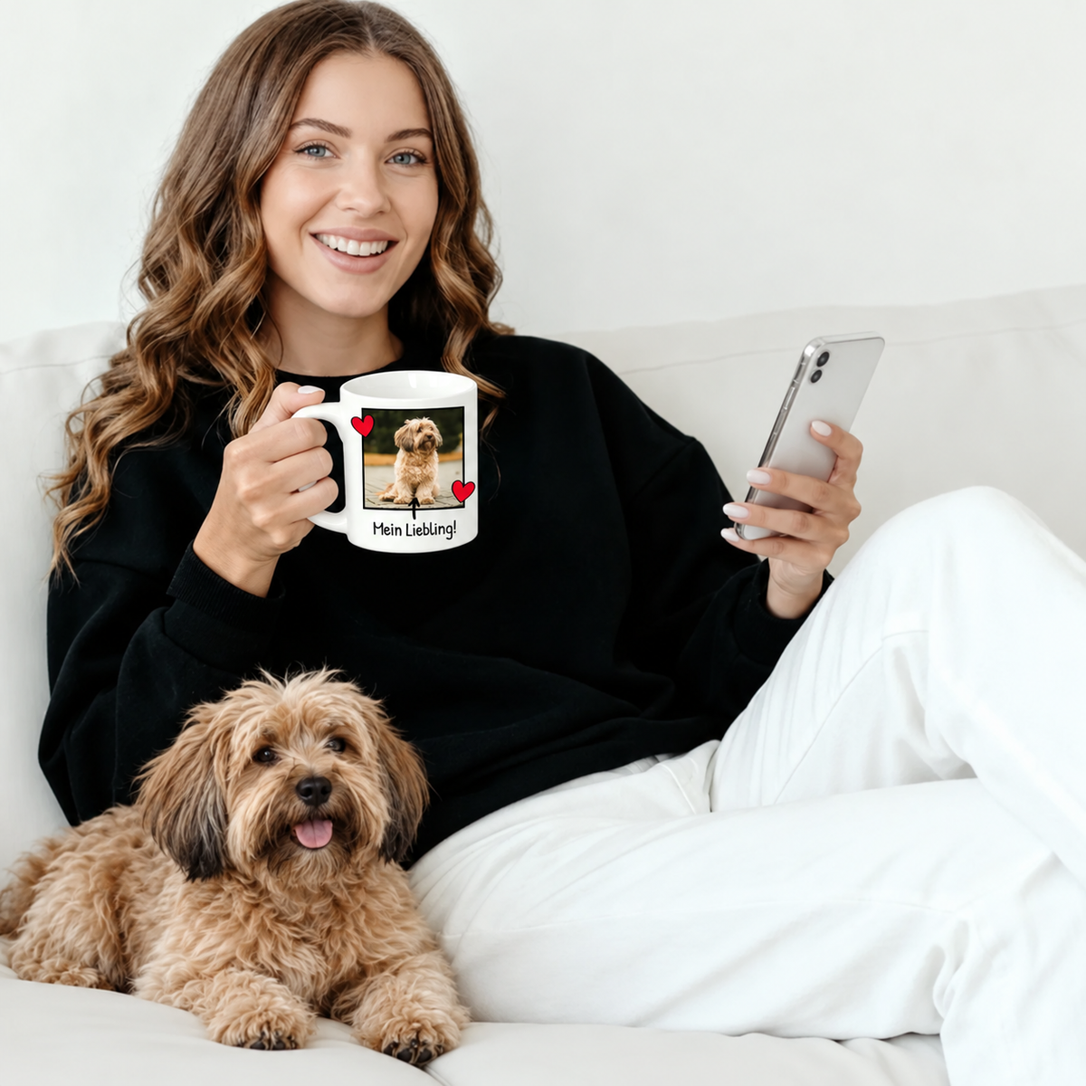 Frau mit personalisierter Fototasse und Hund, sitzend auf einem Sofa, trägt einen schwarzen Pullover.