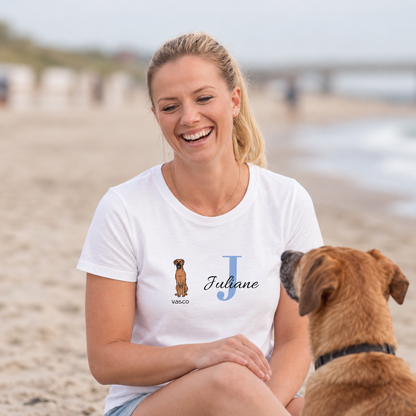 Weißes T-Shirt mit Grafik eines Hundes und dem Namen Juliane in blauen Buchstaben. Frau sitzt am Strand.