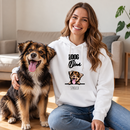 Person mit weißem Hoodie und Hund auf Holzfußboden, lächelnd in wohnlichem Ambiente. Hoodie zeigt Grafik eines Hundes.