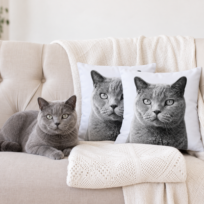 Zwei personalisierte Kissen mit schwarz-weißen Haustierportraits, neben einer grauen Katze auf einer Couch.
