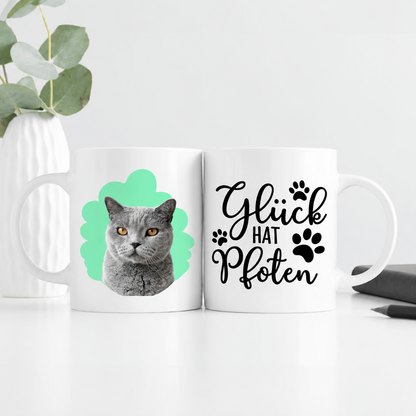 Personalisierte weiße Tasse mit Katzenportrait und Spruch „Glück hat Pfoten“ in schwarzer Schrift.