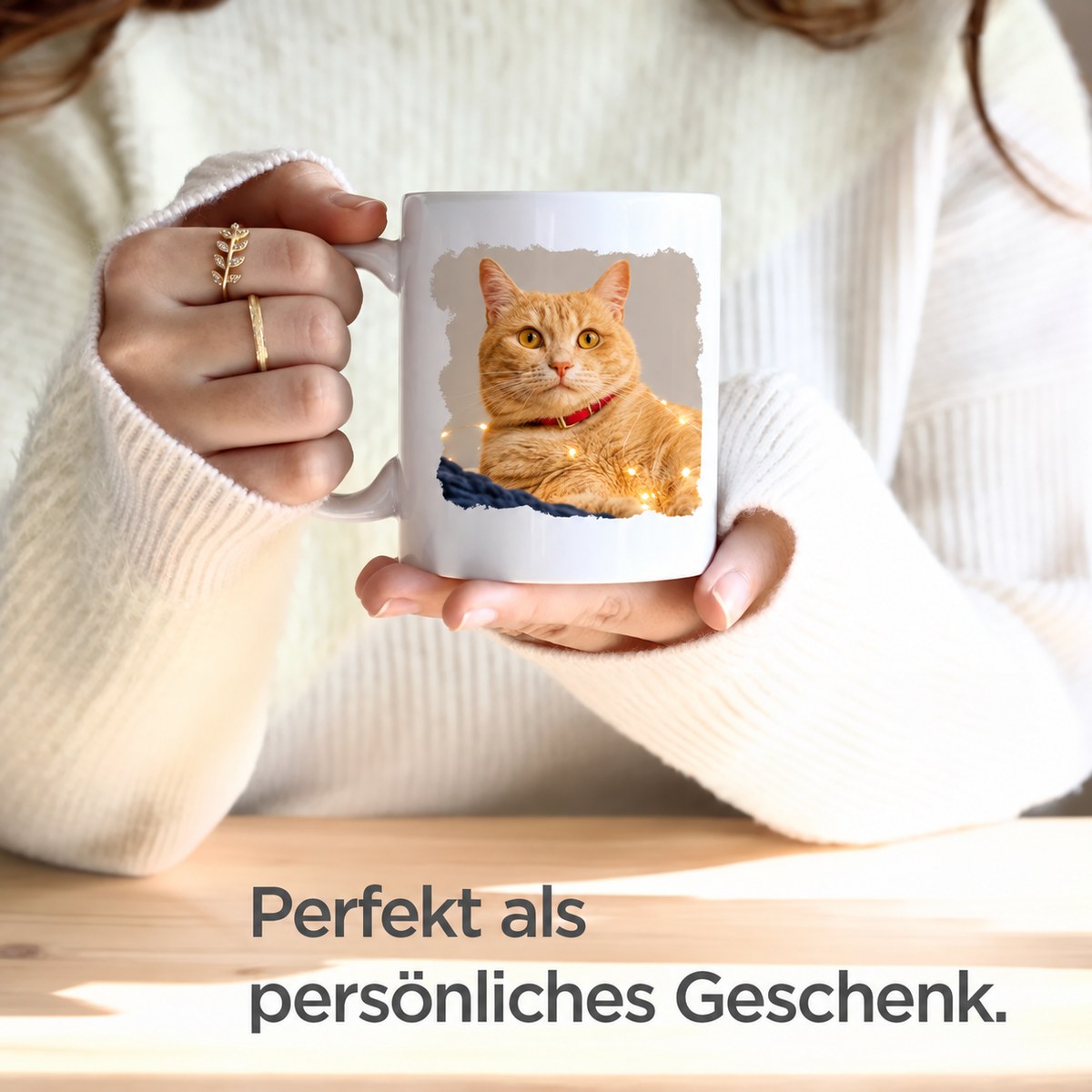 Person hält eine weiße Tasse mit einem Foto eines orangefarbenen Katers darauf.