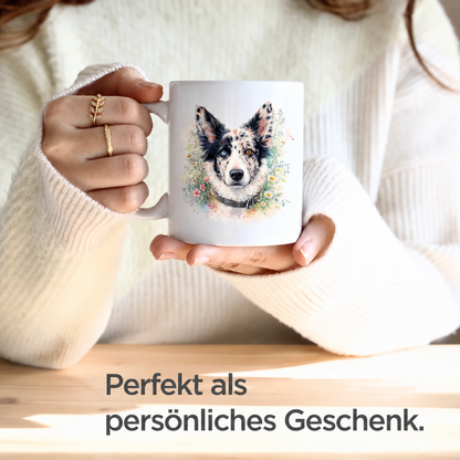 Person hält eine personalisierte Tasse mit Aquarellmotiv eines Hundes in der Hand. Tasse ist weiß mit bunten Blumen.