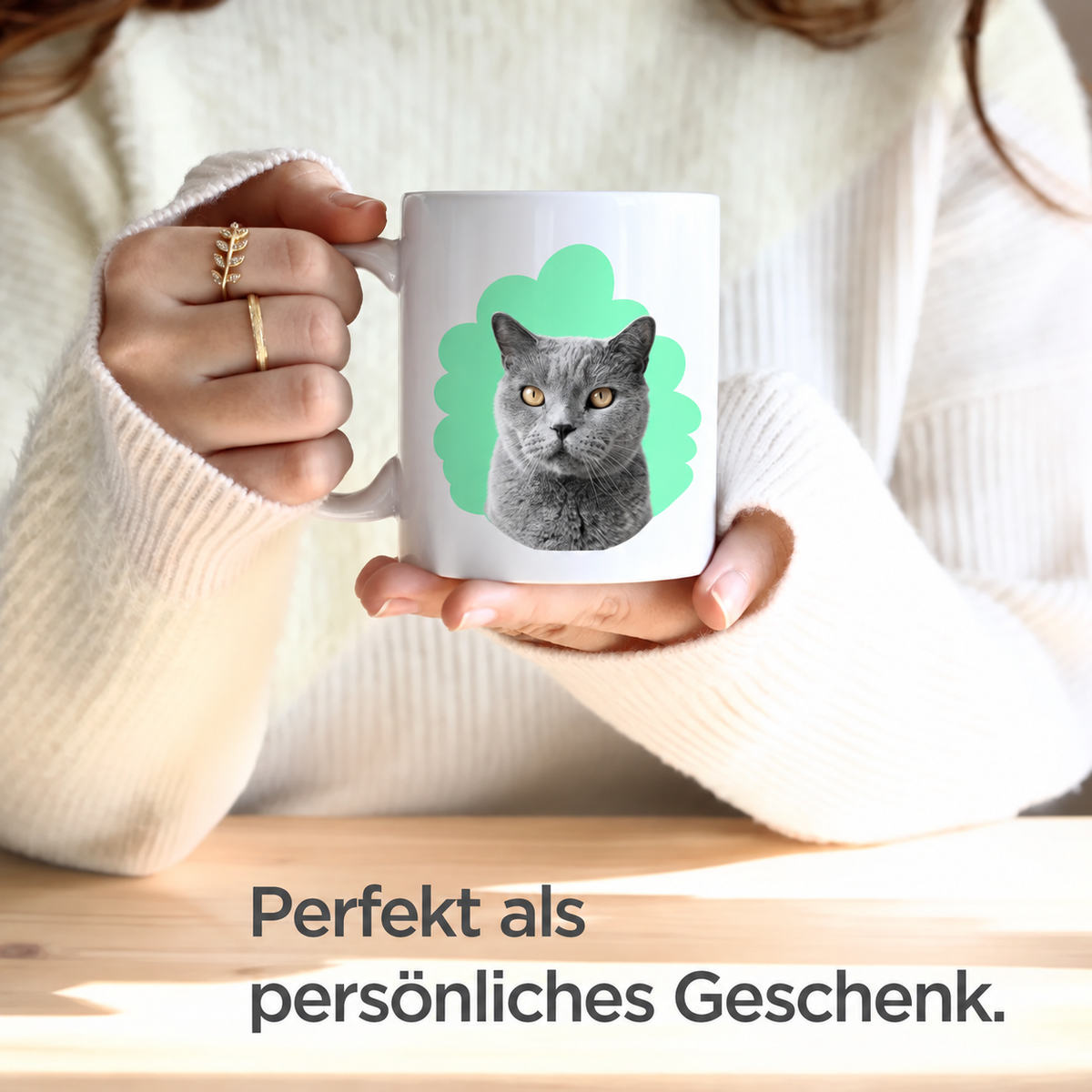 Person hält eine weiße Tasse mit einem Kater-Porträt auf mintgrünem Hintergrund.