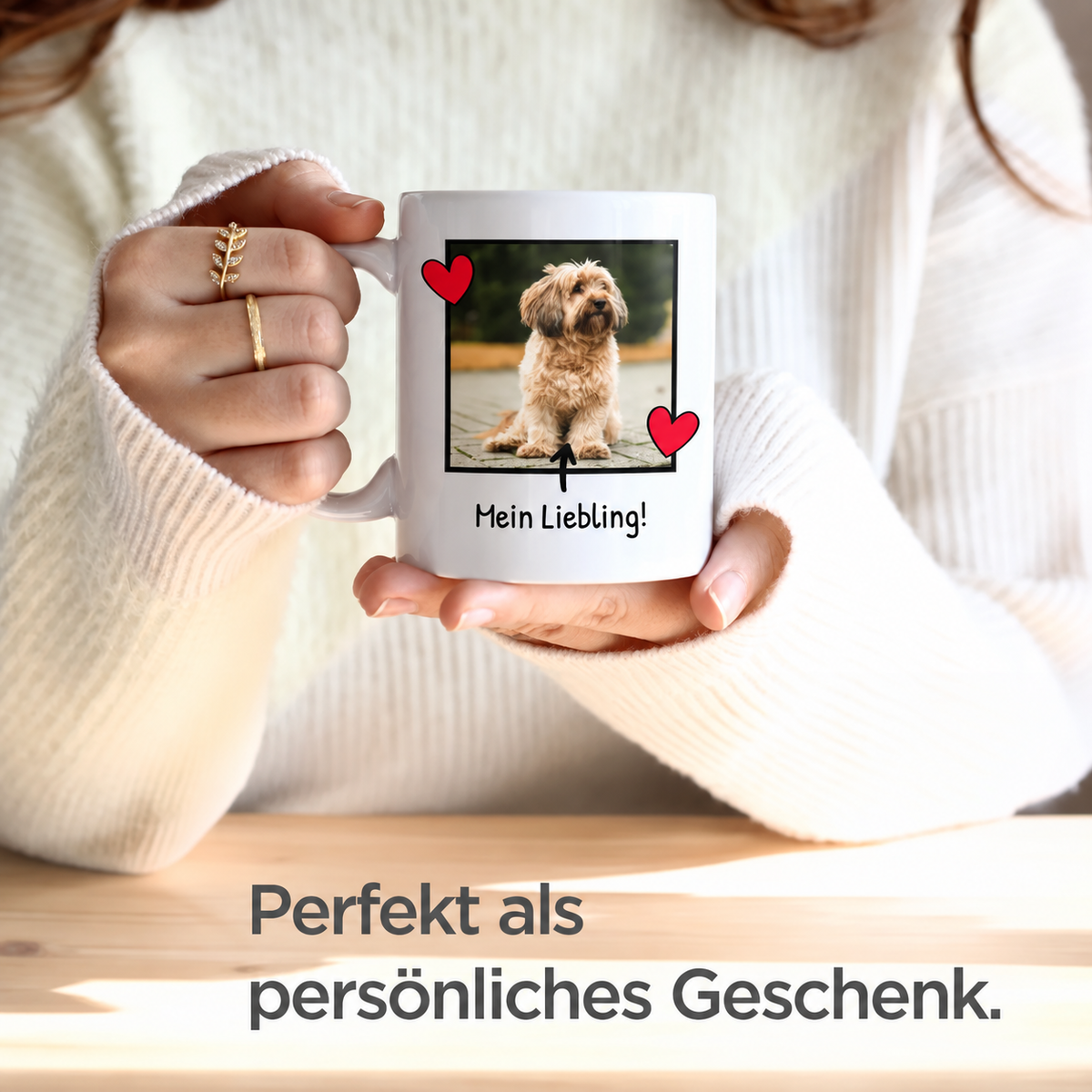 Person hält eine weiße Fototasse mit Hundebild und Schriftzug in der Hand, warme Strickjacke.