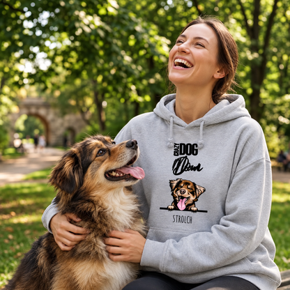 Gris-grauer Hoodie mit Hundemotiv, sitzt auf einer Frau im Park, die mit ihrem Hund spielt und lacht.