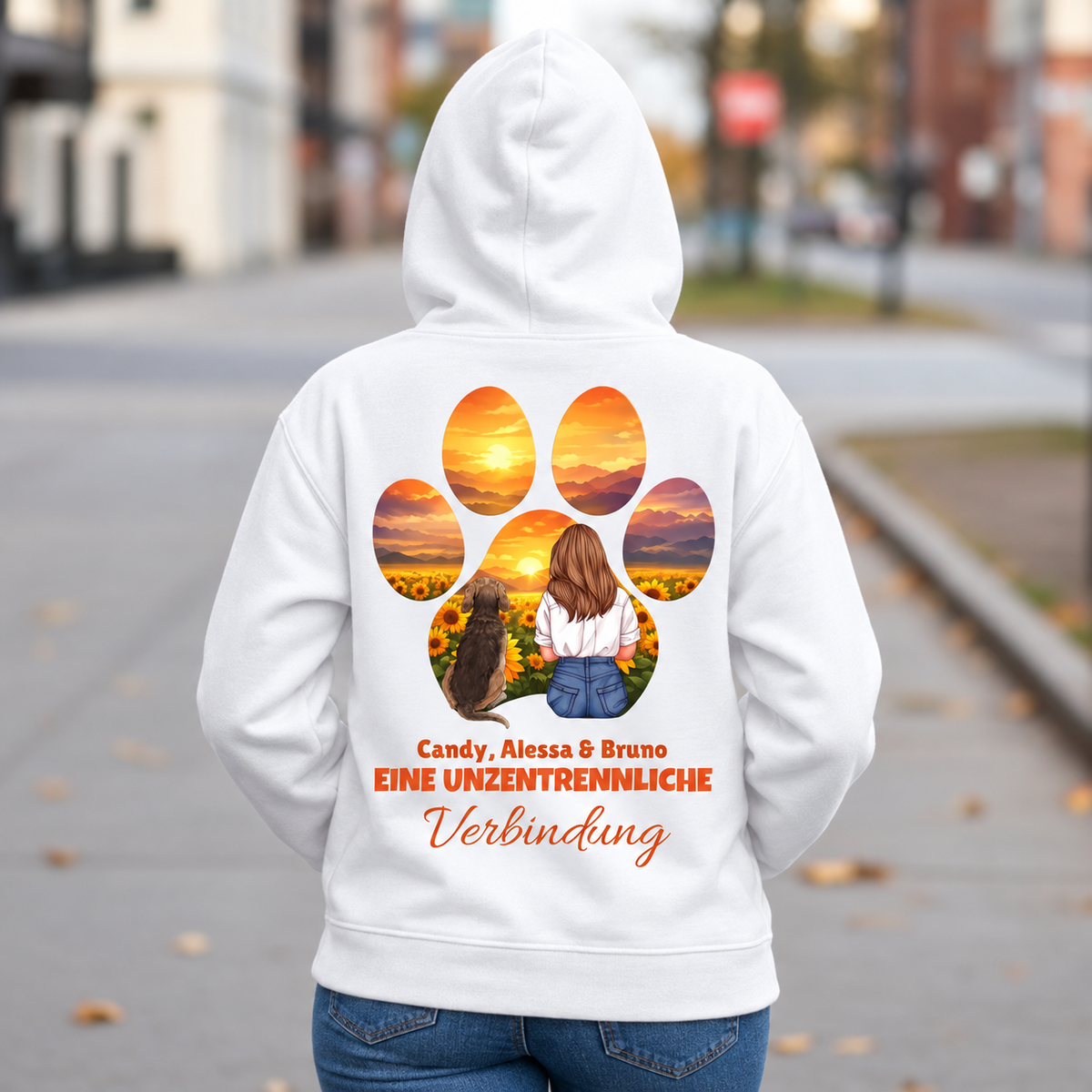 Weißer Hoodie mit Aufdruck einer Person und Hund vor Sonnenuntergang, Text: "Eine unzertrennliche Verbindung".