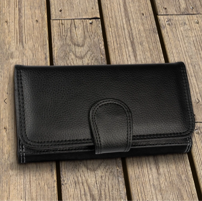 Schwarzes, personalisiertes Portemonnaie aus Leder mit Druckknopfverschluss auf Holzuntergrund.