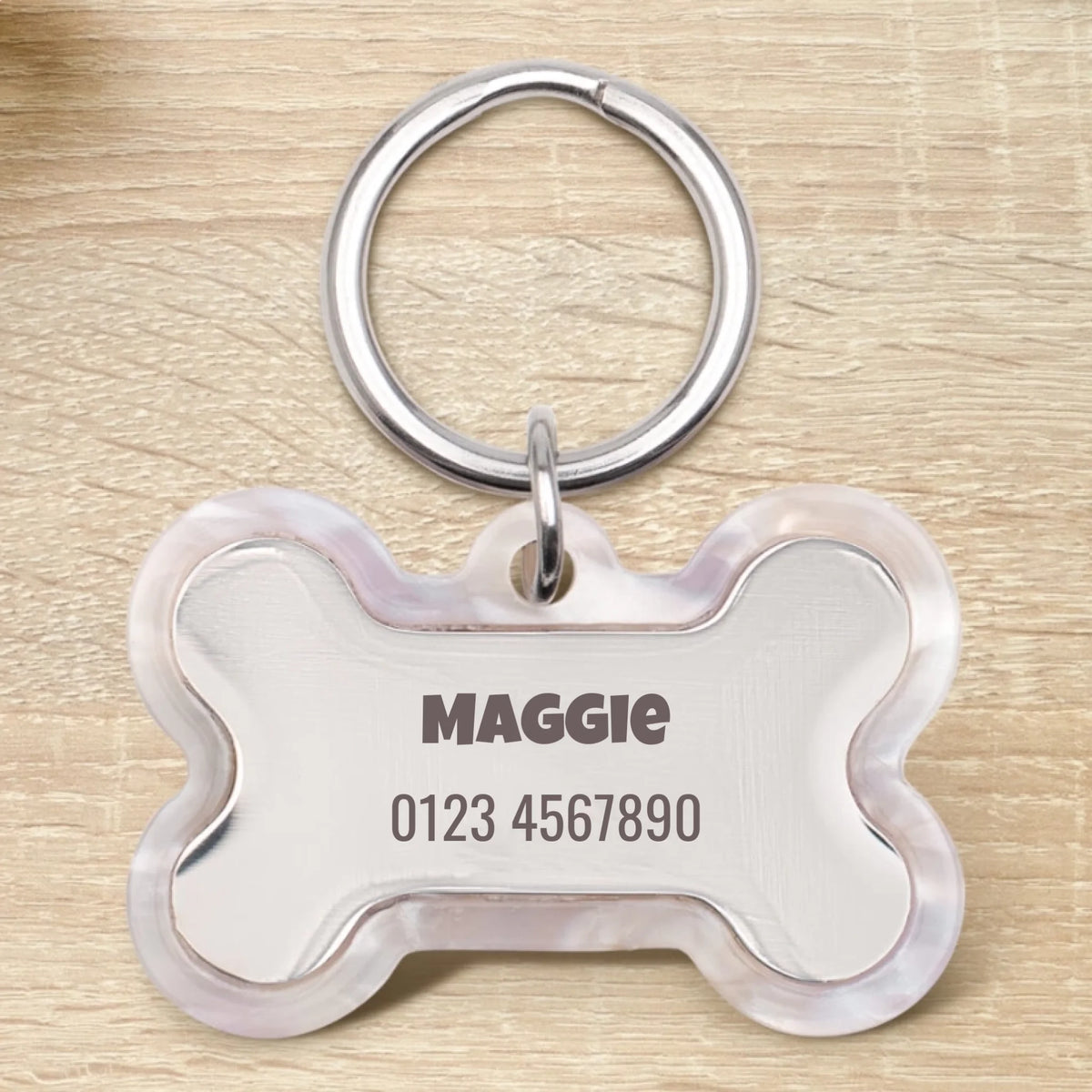Personalisierte Epoxid Hundemarke in Knochenform mit dem Namen Maggie und einer Telefonnummer.