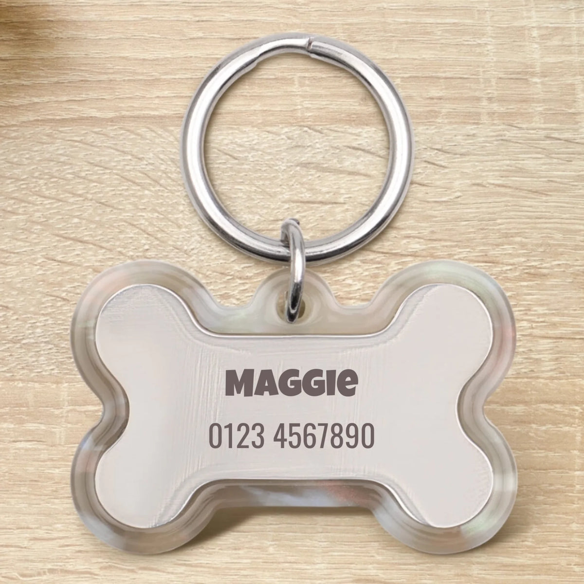 Personalisierte Epoxid Hundemarke in Knochenform mit dem Namen "Maggie" und einer Telefonnummer.