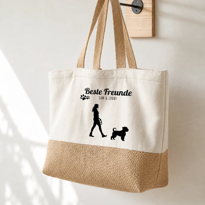 Beige Einkaufstasche mit schwarzem Aufdruck, Silhouette von Mensch und Hund, personalisiert mit Namen.