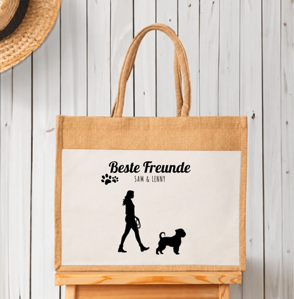 Personalisierte Einkaufstasche aus Jute mit schwarzen Silhouetten von Mensch und Hund. Beschriftung „Beste Freunde“.