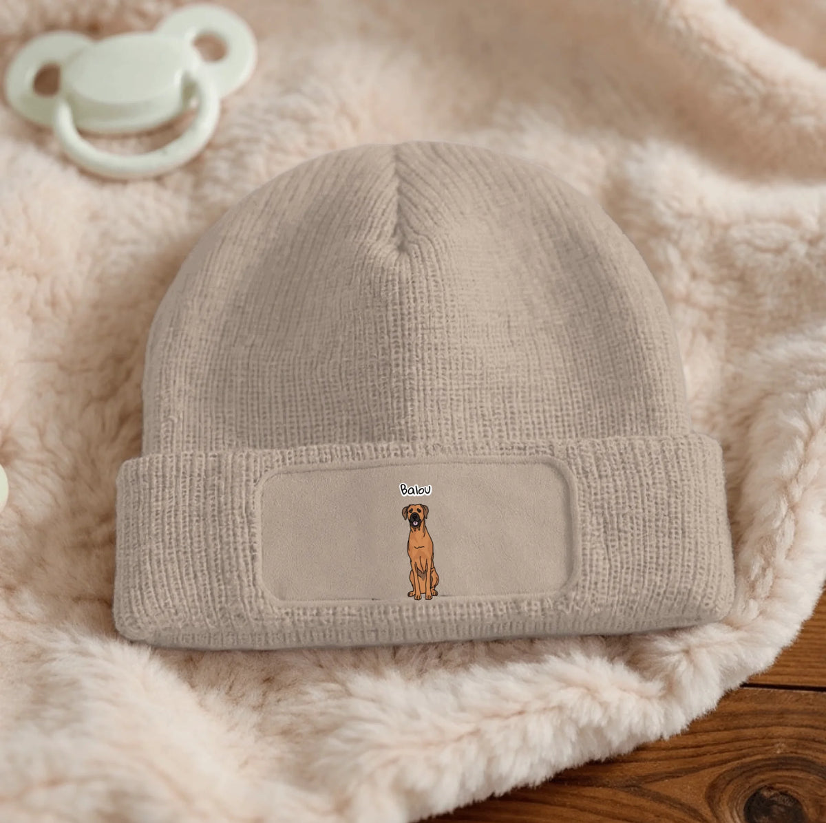 Beige, personifizierte Beanie mit aufgesticktem Hunde-Motiv auf der Vorderseite.