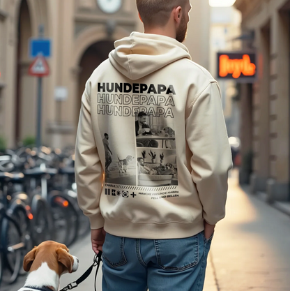 Beige Hoodie mit Aufdruck "Hundepapa" und Bildern von Hunden, getragen von einer Person im urbanen Umfeld.
