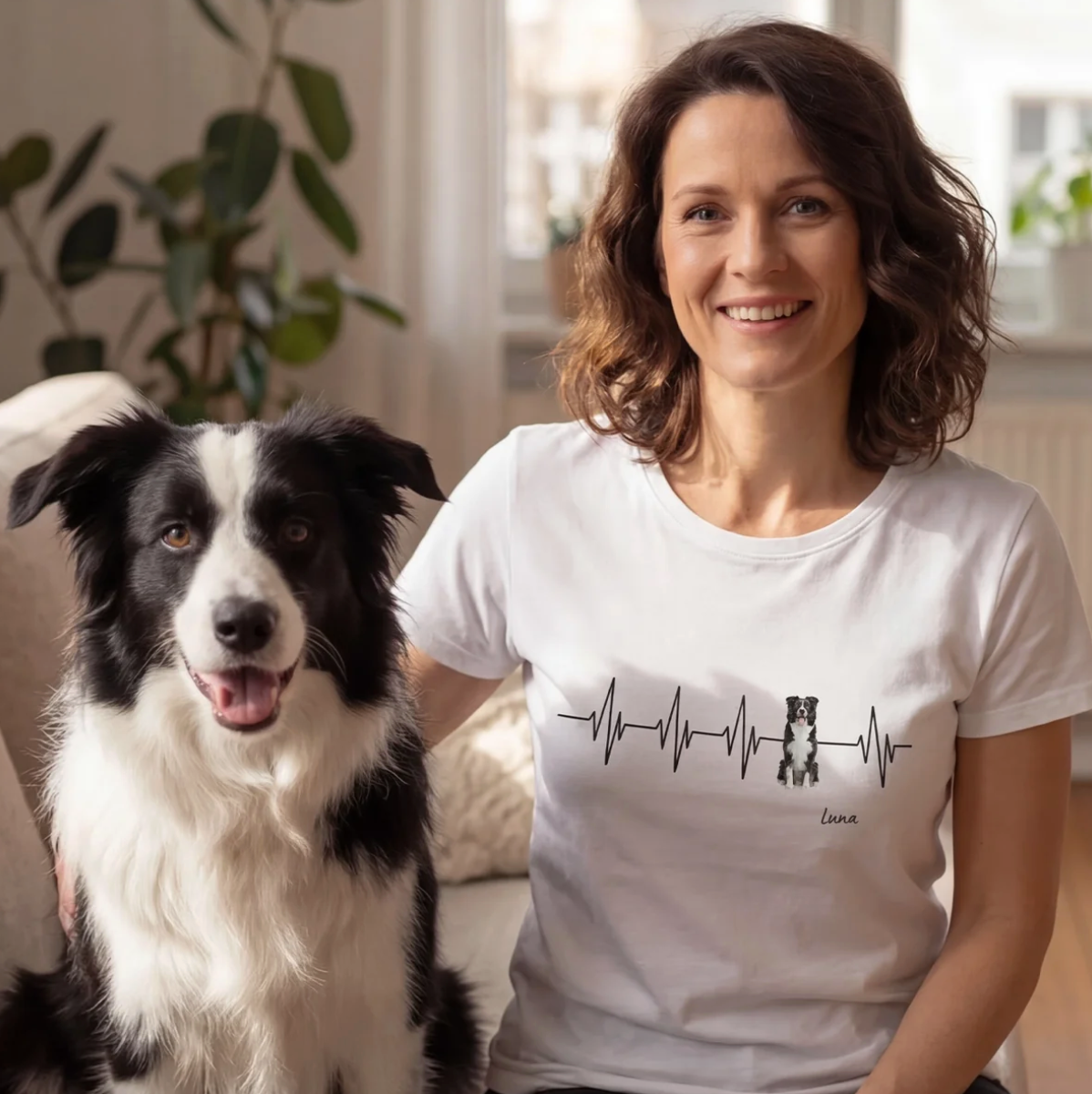 Weißes T-Shirt mit Herzschlag-Design und Hundemotiv, Personalisierung möglich. Frau sitzt mit Hund auf einem Sofa.