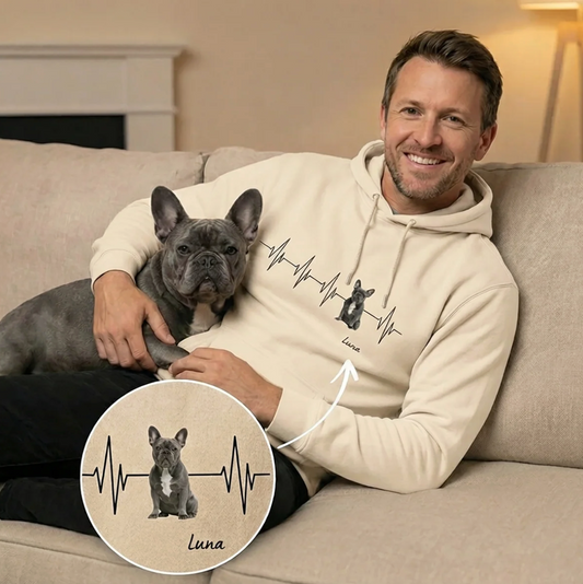 Hochwertiger beige Hoodie mit Herzschlag-Motiv und Hundeporträt, ein Mann hält einen Hund auf der Couch.